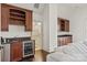 A home bar area features a beverage refrigerator, dark wood cabinetry, and granite countertops near a living space at 314 Royal Crescent Ln, Waxhaw, NC 28173