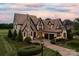 Charming Tudor-style home boasting stone accents, a brick driveway, and lush landscaping at 314 Royal Crescent Ln, Waxhaw, NC 28173