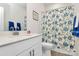 Bright bathroom features a single sink vanity with white cabinets and a shower with a blue floral curtain at 3532 Tully Ave, Kannapolis, NC 28081