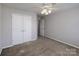 Bright bedroom with neutral carpet, ceiling fan, closet, and a window offering outdoor views at 5000 Tulip Ln, Matthews, NC 28104