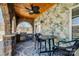 Covered patio with a ceiling fan, grill, dining set, and decorative stone wall at 5000 Tulip Ln, Matthews, NC 28104