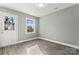 A bright bedroom features an exterior door, an adjacent window, and gray wood-look floors at 515 Fallingswood Ct, Charlotte, NC 28217