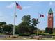 Community entrance showcasing flags, clock tower and manicured landscaping at 7001 Conifer Cir, Indian Trail, NC 28079