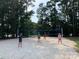 A sand volleyball court with 4 players in a green tree setting at 7001 Conifer Cir, Indian Trail, NC 28079