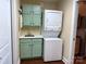 Laundry room with sage green cabinets, sink, and stackable washer and dryer at 822 Wisteria Way, Salisbury, NC 28146