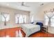 Bright main bedroom featuring hardwood floors, multiple windows with curtains, and a ceiling fan at 9741 Turning Wheel Dr, Charlotte, NC 28214