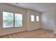 Bright bedroom featuring carpet, neutral walls, two windows with blinds, and a closet door at 1012 Equipoise Dr, Indian Trail, NC 28079