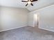 Spacious bedroom with neutral carpet, a ceiling fan, and a walk-in closet at 12915 Deaton Hill Dr, Charlotte, NC 28269