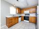 Functional kitchen with stainless steel sink, white appliances, tile floor, and wooden cabinets at 12915 Deaton Hill Dr, Charlotte, NC 28269
