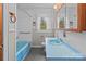 Well-lit bathroom featuring a blue sink, toilet, and tub, complemented by white tiled walls at 136 Coble Ave, Albemarle, NC 28001