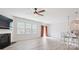 Bright living room featuring a fireplace, ceiling fan, large windows, and an open floor plan leading to the kitchen at 15119 Oleander Dr, Charlotte, NC 28278
