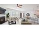 Bright living room featuring a fireplace, ceiling fan, large windows, and an open floor plan leading to the kitchen at 15119 Oleander Dr, Charlotte, NC 28278