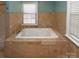 Elegant bathroom featuring a luxurious soaking tub with travertine tile surround and natural light at 2046 Cartier Way, Charlotte, NC 28208