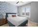 Comfortable bedroom with wallpapered accent wall, a large window, and a well-lit, inviting ambiance at 210 Freeland Ln, Charlotte, NC 28217