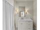 A bright bathroom featuring a white vanity, marble countertop, decorative mirror, and shower with curtain at 2251 Selwyn Ave # 201, Charlotte, NC 28207