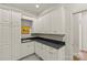 The laundry room is equipped with white cabinets, granite countertops, and stainless steel sink at 2251 Selwyn Ave # 201, Charlotte, NC 28207