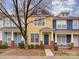 Charming yellow townhome featuring a brick foundation, covered porch, and vibrant blue accents at 244 Hurston Cir, Charlotte, NC 28208