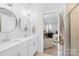 Bright bathroom featuring dual sinks, modern lighting, and a view into the main bedroom at 3512 Auburn Curb Rd, Charlotte, NC 28217