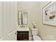 Charming powder room with dark wood vanity, white sink and toilet, decorative mirror, and artwork at 11311 Mcclure Manor Dr, Charlotte, NC 28277