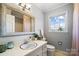Bright bathroom featuring a large mirror, vanity with sink, toilet, and natural light from the window at 1148 Turnbridge Rd, Charlotte, NC 28226