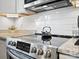 Close-up of stainless steel stove top with tile backsplash and granite countertops at 125 Ashe St, Gastonia, NC 28056