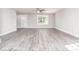 Open living room with hardwood floors, a ceiling fan, a window, and a white door at 1308 Jay Ave, Gastonia, NC 28052