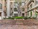 Brick building with a manicured courtyard featuring a tree, bushes, brick planters, and balconies with metal railings at 1333 Queens Rd # B1, Charlotte, NC 28207