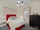 Bright bedroom features a red upholstered bed with patterned pillows, and a window with matching curtains at 2004 Lombardy Cir, Charlotte, NC 28203