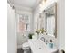 Bright bathroom with a decorative mirror, white pedestal sink, and window providing natural light at 2009 Charlotte Dr, Charlotte, NC 28203