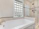 Bright bathroom featuring a soaking tub, glass shower, and a window with block glass at 2009 Charlotte Dr, Charlotte, NC 28203