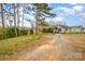 Exterior view of a home with gravel driveway, lawn, and mature trees on a partly cloudy day at 202 Hovis Rd, Stanley, NC 28164