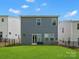 View of the home's back exterior, with a well-maintained lawn and full sliding glass door at 518 Palmarosa St, Fort Mill, SC 29715