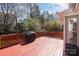 View of the red back deck with grill, overlooking private backyard with mature trees at 7533 Lady Bank Dr, Charlotte, NC 28269