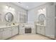 Bright bathroom features dual vanities, soaking tub with shuttered window, and neutral tiling at 7704 Sharpthorne Pl, Charlotte, NC 28270