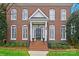 Elegant brick facade showcasing the front door entrance with classic design and manicured landscaping at 7704 Sharpthorne Pl, Charlotte, NC 28270