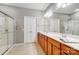 Bright bathroom with a double vanity, large mirror, and a glass-enclosed shower, plus linen storage at 9005 Smokey Hill Ln, Indian Land, SC 29707