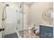 Stylish bathroom with a glass shower, patterned floor tiles, and a decorative circular mirror at 9260 Ahavah Ln, Indian Trail, NC 28079