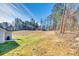The backyard presents a spacious landscape with a view of towering trees and a lush lawn at 1076 Westminster Dr, Lancaster, SC 29720