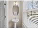 Cozy powder room with a pedestal sink, decorative mirror and natural light from the window at 15662 King Louis Ct, Charlotte, NC 28277