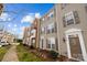 Inviting townhomes showcasing neutral siding, complemented by well-manicured landscaping and shuttered windows under a sunny sky at 15662 King Louis Ct, Charlotte, NC 28277