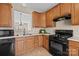 Well-lit kitchen featuring wood cabinets, black appliances, and a view into the adjacent room at 15662 King Louis Ct, Charlotte, NC 28277