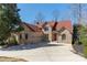 A brick home with a red roof has an attached garage, and large driveway and is surrounded by greenery and bare trees at 170 W Maranta Rd, Mooresville, NC 28117