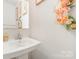 Elegant powder room features a decorative mirror, attractive floral arrangements, and pedestal sink, creating a welcoming ambiance at 2311 Doby Creek Ln, Charlotte, NC 28262