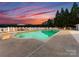 Sunset view of a beautiful pool with lounge chairs and a covered patio overlooking the tranquil lake waters at 249 Blue Heron Dr, Rock Hill, SC 29732