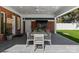 The covered patio has an outdoor ceiling fan, dining table with seating, and brick wall with mounted television at 2701 Sharon Rd, Charlotte, NC 28211