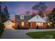 Attractive brick home with well-lit windows, dormers, and a detached garage on a paved driveway at 2701 Sharon Rd, Charlotte, NC 28211