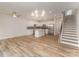 Open-concept living room and kitchen with hardwood floors, stainless appliances, staircase, and modern lighting at 2816 Old Steele Creek Rd, Charlotte, NC 28208