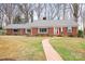 Charming single-story brick home featuring a walkway, manicured lawn, and mature trees at 329 N Oakwood Dr, Statesville, NC 28677