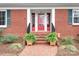 Charming brick home entrance featuring a red door flanked by decorative windows and lush ferns at 329 N Oakwood Dr, Statesville, NC 28677