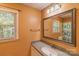 Bathroom with orange walls, grey countertop, window and a large decorative mirror at 3430 Olde Oak Ln, Gastonia, NC 28056